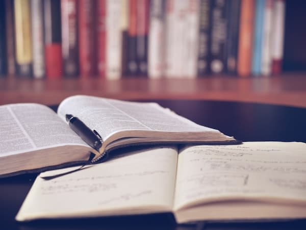Open notebook and fountain pen beside reading shelf
